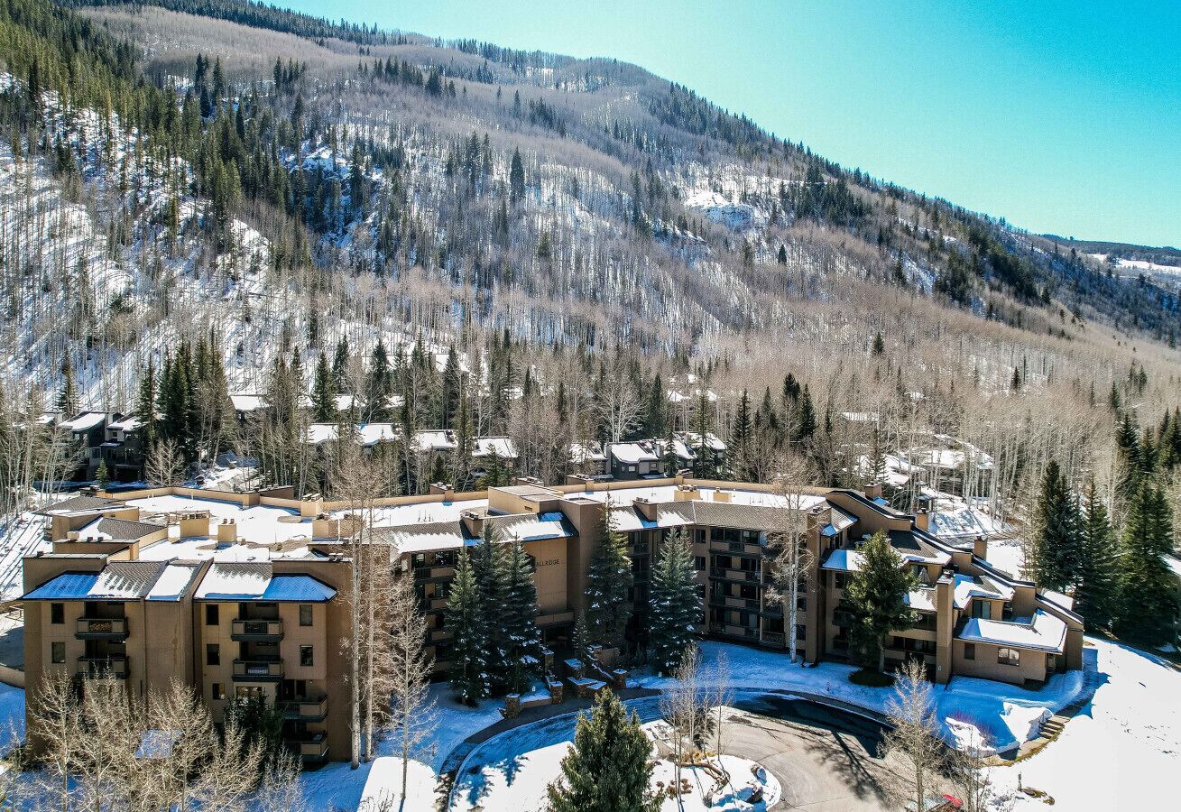 A multi-story hotel with a central courtyard, surrounded by snow-covered terrain and trees.