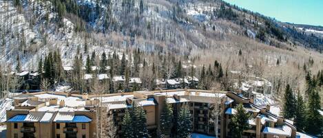 A multi-story hotel with a central courtyard, surrounded by snow-covered terrain and trees.