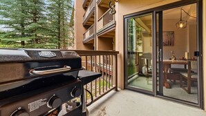 Een barbecue op een balkon met uitzicht op een eethoek en bomen.