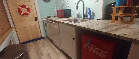A compact kitchen with a microwave, sink, and a red Coca-Cola refrigerator.