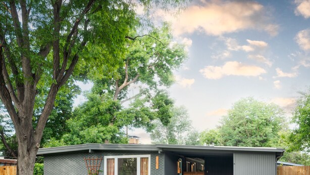 Et moderne hus i et plan med stort vindue, garage og velplejet græsplæne.