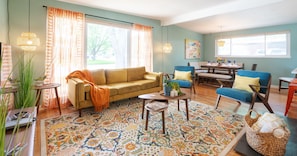 A living room with a sofa, chairs, a coffee table, and a patterned rug. - Retro Rooms: Ping-Pong, Fire-Pit, Game Room, Families + Dogs + Fenced Yard (Arvada)