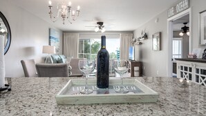 A dining area with a granite countertop, a bottle, and two wine glasses on a tray. - Amalfi Coast B219 * Scenic 98 near restaurants * Salt Water Vacations (Destin)
