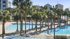 A resort with multiple swimming pools surrounded by palm trees and lounge chairs. - Amalfi Coast B219 * Scenic 98 near restaurants * Salt Water Vacations (Destin)