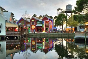 Een waterkant met gebouwen, verlichte reclameborden, een steiger en een watertoren.