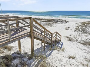 Une promenade en bois qui mène à une plage aux eaux d’un bleu limpide.
