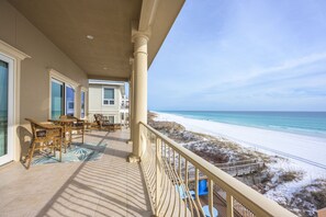 A balcony with wicker furniture overlooking a beach. - Gulf Paradise * Golf Cart & Beach Chair Set * Gulf Front * Salt Water Vacations (Miramar Beach)