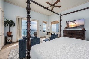 A bedroom with a four-poster bed, a ceiling fan, a large window with a view of the ocean, a television, and a dresser. - Gulf Paradise * Golf Cart & Beach Chair Set * Gulf Front * Salt Water Vacations (Miramar Beach)