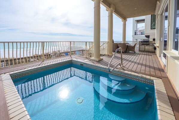 Un espace piscine avec vue sur l’océan, une terrasse couverte et un barbecue.