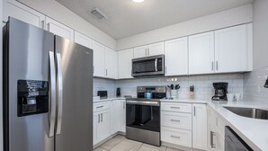A modern kitchen with white cabinets, stainless steel appliances, and a tiled backsplash. - Gulf Winds East 22 * Fall Specials * Across from beach * Salt Water Vacations (Destin)