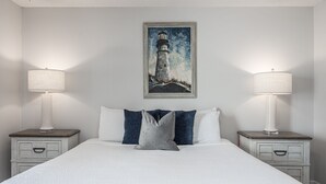 A neatly made bed with white bedding and two pillows, flanked by nightstands with lamps and drawers. - Gulf Winds East 22 * Fall Specials * Across from beach * Salt Water Vacations (Destin)