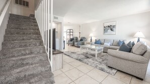 A modern living room with a staircase, a sofa set, and a coffee table. - Gulf Winds East 22 * Fall Specials * Across from beach * Salt Water Vacations (Destin)