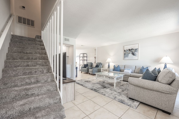 A modern living room with a staircase, a sofa set, and a coffee table.
