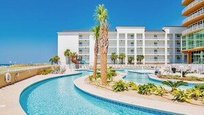A hotel with a large pool area, palm trees, and a clear blue sky. - Phoenix Gulf Tower 1704 | Spacious, luxurious, Newest OBA development! (Orange Beach)