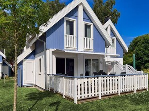 Ein zweistöckiges Haus mit weißem Wintergarten und einem kleinen Balkon.