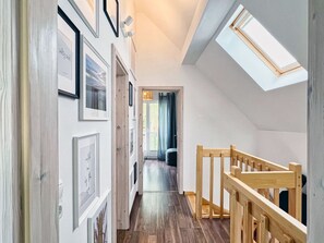 A narrow hallway with wooden flooring, white walls, and a skylight.