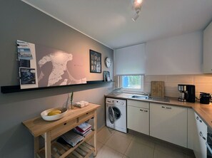 A modern kitchen with a washing machine, a coffee maker, and a window with a view.