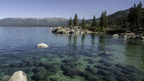 A clear lake with visible rocks and mountains in the background. - NorthStar Lodge at Lake Tahoe in walking distance to ski lifts! (Truckee)