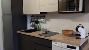 Eine kleine Küche mit integriertem Waschmaschine, einer Mikrowelle und einem Spülbecken.