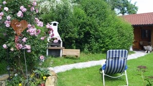 Un jardin avec un banc en bois, une chaise à rayures et un panneau en forme de cœur.