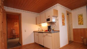 Une cuisine de taille réduite, dotée de meubles en bois, d’un four à micro-ondes et d’un évier.