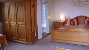 Une chambre à coucher avec une armoire en bois, un lit avec une literie rouge et blanche, et un mur orné d’une inscription décorative.