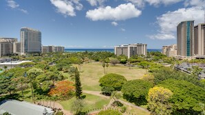Un hotel de gran altura con varios pisos, un patio central con vegetación y vistas al océano.