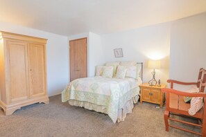A bedroom with a bed, wooden wardrobe, nightstand, and a chair. - The Love Shack (Sugarloaf)
