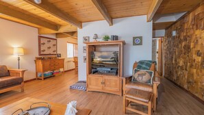 A cozy living room with wooden furniture, a television cabinet, and a wall with a wooden panel design. - The Love Shack (Sugarloaf)
