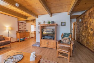 A cozy living room with wooden furniture, a television cabinet, and a wall with a wooden panel design.