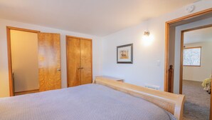 A bedroom with a large bed, wooden wardrobe, and a small bedside table. - The Love Shack (Sugarloaf)