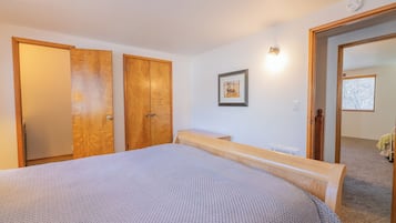 A bedroom with a large bed, wooden wardrobe, and a small bedside table.