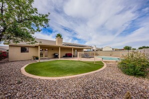 A residential backyard with a swimming pool, covered patio, and a well-maintained lawn. - Oasis de Saguaro 3-Bedroom home with pool (Tucson)