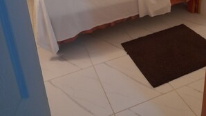 Un lit simple avec une tête de lit en bois, une literie blanche et un rideau de couleur turquoise.