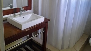 Une salle de bain avec un lavabo blanc, un miroir et un rideau de douche.