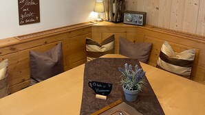 A cozy dining area with a wooden table, cushioned benches, and a chandelier.