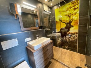 Un baño moderno con un espejo grande, un lavamanos y una decoración de ciervo en la pared.