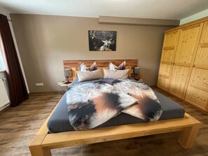Una camera da letto con una struttura letto in legno, un copriletto grande, una testiera con un quadro e un'armadio in legno.