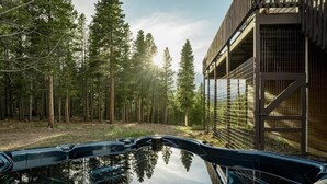 A hot tub in a forested area with a building in the background.