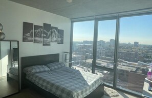 Enjoy a panoramic city view from the comfort of this stylish bedroom, featuring a large bed and a minimalist design.