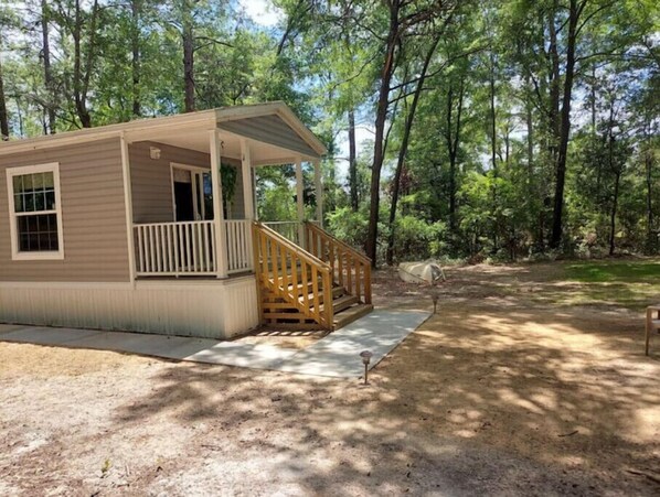 Escape to a serene cabin surrounded by a wooded area, featuring a porch and a deck with a staircase.