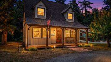 Un accogliente chalet con un portico, un piccolo spazio salotto all'aperto e un cartello che indica che si tratta di una 'Little Beer Cottage'.