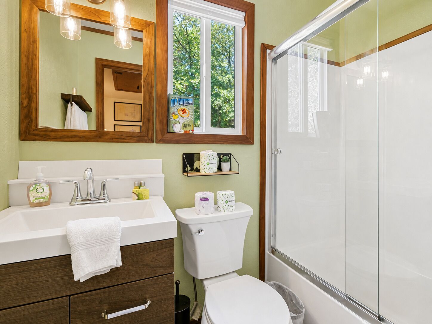 A bathroom with a white sink, a mirror, a toilet, and a glass-enclosed shower.