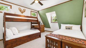 A bedroom with a bunk bed, a single bed, a ceiling fan, a window, and a green wall.