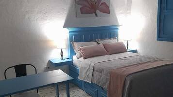 A bedroom with a bed, a desk, and a chair.