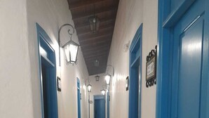 Un pasillo con puertas azules y paredes blancas que da a una habitación.