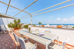 A terrace with a table and chairs, a bottle of wine, and a view of the sea.