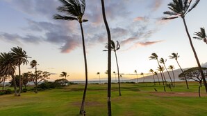 A golf course with palm trees and a view of the ocean at sunset. - Modern & Elegant Oceanfront Vistas (Kihei)
