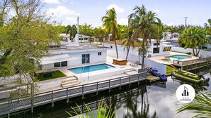 A residential area with a swimming pool, a dock, and a clear sky. - Stylish Aventura Home With Pool on Intercostal (Ojus)