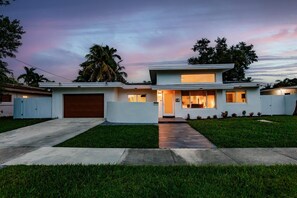 A modern two-story house with a garage, a well-maintained lawn, and a clear sky. - Stylish Aventura Home With Pool on Intercostal (Ojus)